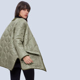 Oversized green women's quilted puffer jacket displayed on a model, showcasing its lightweight and casual design suitable for autumn. The jacket features a high collar, long sleeves, and a quilted pattern.