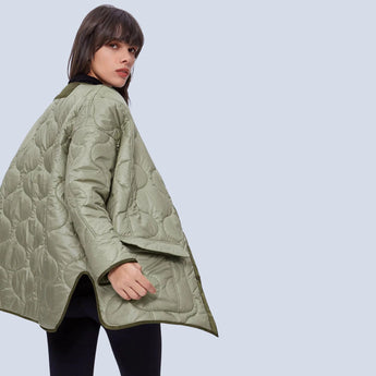 Oversized green women's quilted puffer jacket displayed on a model, showcasing its lightweight and casual design suitable for autumn. The jacket features a high collar, long sleeves, and a quilted pattern.