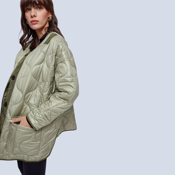 Oversized green women's quilted puffer jacket, lightweight and casual for autumn, featuring a high collar and long sleeves.