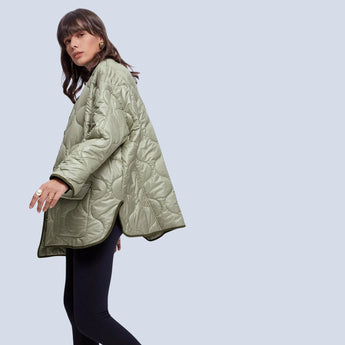Oversized green women's quilted puffer jacket, lightweight and casual for autumn, featuring long sleeves, a high collar, and a knee-length design.