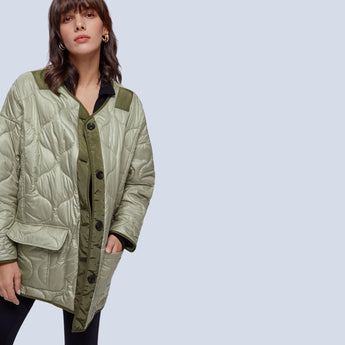 Woman wearing an oversized green quilted puffer jacket with a collar and long sleeves, suitable for lightweight, casual autumn wear.
