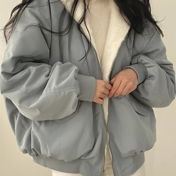 Oversized grey puffer jacket for women, showcasing a fashionable winter coat design with long sleeves and a high neck, emphasizing comfort and warmth.
