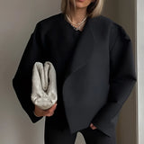 
Woman wearing an oversized grey sweater paired with a gold chain bag, showcasing trendy women's casual wear. Her arm and shoulder are visible, and she is wearing sunglasses. The sweater is in the Nero color variant and XL size.