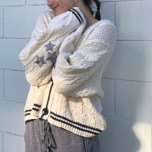 Oversized white knit sweater with star pattern, featuring long sleeves and a cozy fit, modeled by a person showcasing the shoulder and neck areas.
