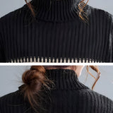 Oversized chunky knit turtleneck sweater dress with black and white stripes, featuring long sleeves and a cozy winter design.