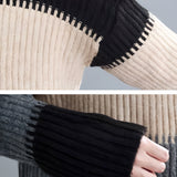 Oversized turtleneck striped sweater dress in chunky knit fabric, featuring black and white stripes and long sleeves, displayed in a well-lit setting with a hint of greenery in the background.