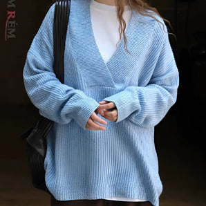 Oversized women's blue knit sweater featuring a deep V-neck design, long sleeves, and a cozy fit suitable for winter wear. The sweater appears to have a relaxed fit around the shoulders and waist, effectively showcasing its casual and comfortable style.