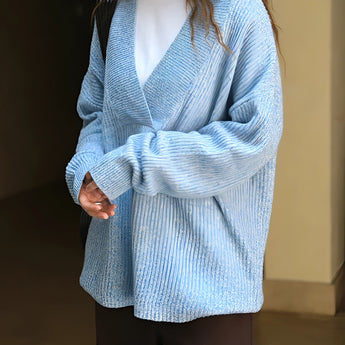 Oversized women's blue knit sweater with a deep V-neck, featuring long sleeves and a cozy, relaxed fit suitable for winter wear.