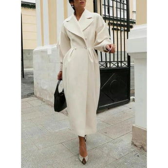 Oversized women's wool trench coat in beige, featuring a double-breasted design with a wide collar, long sleeves, and a tailored waist, styled elegantly for winter wear.