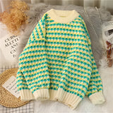 A cozy soft knit pullover sweater featuring a pastel pink and green houndstooth pattern, displayed in a 3XL size. The garment is hanging on a clothes hanger, showcasing its long sleeves and comfortable design.
