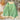 A cozy soft knit pullover sweater featuring a pastel pink and green houndstooth pattern, displayed in a 3XL size. The garment is hanging on a clothes hanger, showcasing its long sleeves and comfortable design.
