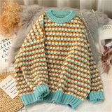 Pastel pink and green houndstooth sweater in a cozy, soft knit fabric, shown in a 3XL size. The sweater features a turquoise accent, with long sleeves and a round neck, displayed on a clothes hanger.