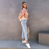 
A chic summer outfit featuring a peach lace blouse paired with acid wash jeans and white sneakers, highlighting the detailed lace design, denim texture, and casual style.