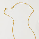 Gold floral pendant necklace with pearl centerpiece displayed on a clothes hanger.