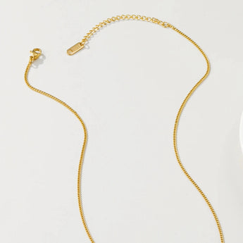 Gold floral pendant necklace with pearl centerpiece displayed on a clothes hanger.