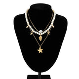 Elegant pearl necklace featuring gold starfish and seashell charms, perfect for beach-inspired fashion and jewelry enthusiasts.