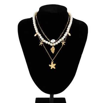 Elegant pearl necklace featuring gold starfish and seashell charms, perfect for beach-inspired fashion and jewelry enthusiasts.