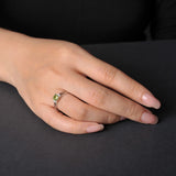 Sterling silver ring with a cushion-cut green peridot gemstone and small diamonds on a person's finger.