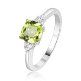 Sterling silver ring with a cushion cut green peridot gemstone and small diamonds on the band, displayed on a person's finger.