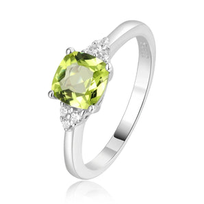 Sterling silver ring with a cushion cut green peridot gemstone and small diamonds on the band, displayed on a person's finger.
