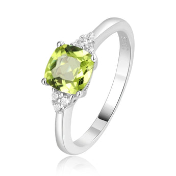 Sterling silver ring with a cushion cut green peridot gemstone and small diamonds on the band, displayed on a person's finger.