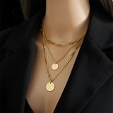 A person wearing a personalized gold chain necklace with an engraved pendant, showcasing its elegant design against the neckline and chest.