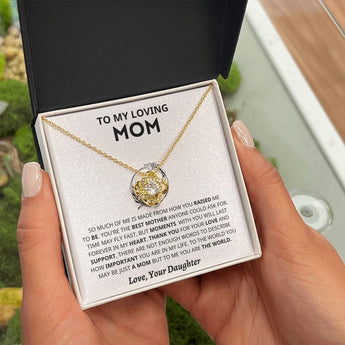 A hand holding a personalized heart-shaped silver necklace with an 18K yellow gold finish, shown in a two-tone box, perfect as a Mother's Day gift from a daughter.
