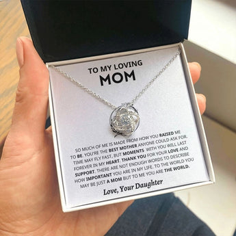 A silver heart-shaped necklace with personalized engraving, displayed being held delicately by someone's fingers, perfect as a Mother's Day gift from a daughter.
