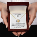 A close-up of a personalized heart-shaped silver necklace, ideal as a Mother’s Day gift from a daughter, being held by a hand with manicured nails.