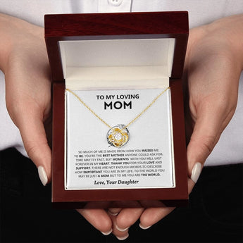 A close-up of a personalized heart-shaped silver necklace, ideal as a Mother’s Day gift from a daughter, being held by a hand with manicured nails.