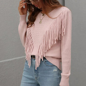 Pink Bohemian Fringe Knit Sweater worn by a woman paired with jeans and a grey fedora hat. The sweater features long sleeves and bohemian fringe detailing. The outfit gives a trendy and stylish look.