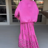 Pink boho skirt paired with an oversized sweater, showcasing a stylish and vibrant spring fashion ensemble for women. The outfit features shades of pink and violet, with a chic pattern design, perfect for a fashionable and comfortable look.