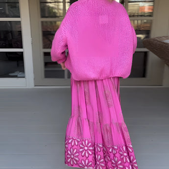 Pink boho skirt paired with an oversized sweater, showcasing a stylish and vibrant spring fashion ensemble for women. The outfit features shades of pink and violet, with a chic pattern design, perfect for a fashionable and comfortable look.