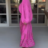 Woman wearing a pink boho skirt paired with an oversized sweater, featuring long sleeves and a relaxed fit, styled with a matching hat for a chic spring fashion look.