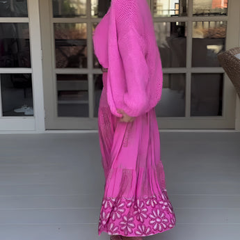 Woman wearing a pink boho skirt paired with an oversized sweater, featuring long sleeves and a relaxed fit, styled with a matching hat for a chic spring fashion look.