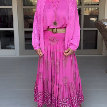
A woman smiling while wearing a light pink oversized sweater and a matching pink boho skirt, showcasing a stylish and comfortable women's spring fashion outfit in size 3XL.