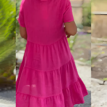 Pink cotton ruffle tiered midi dress with short sleeves, featuring a casual summer style, displayed with vibrant pink and purple hues.