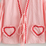 Pink gingham puff sleeve blouse with ruffle trim, featuring a vibrant spring design, displayed on a hanger against a neutral background.