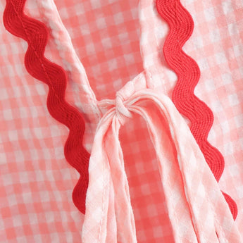 Pink gingham puff sleeve blouse with ruffle trim featuring a plaid pattern and tie detail, perfect for spring fashion.