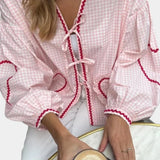 A stylish pink gingham puff sleeve blouse featuring a ruffle trim, perfect for spring fashion.