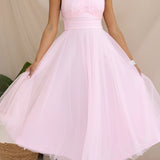 Pink halter neck backless tulle dress, worn by a smiling woman, ideal for weddings and summer events, showcasing a blend of elegance and style with its flowing one-piece design.
