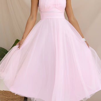 Pink halter neck backless tulle dress, worn by a smiling woman, ideal for weddings and summer events, showcasing a blend of elegance and style with its flowing one-piece design.
