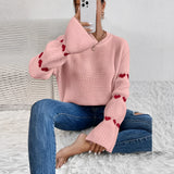 
A cozy pink heart sleeve sweater featuring a soft knitted fabric with long sleeves, perfect for fall fashion. The sweater is styled on a person, highlighting its comfortable fit and vibrant color.
