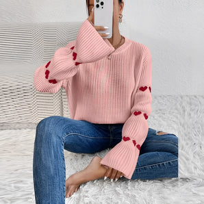 
A cozy pink heart sleeve sweater featuring a soft knitted fabric with long sleeves, perfect for fall fashion. The sweater is styled on a person, highlighting its comfortable fit and vibrant color.