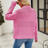 Pink textured ribbed sweater with a unique cut-out design, showcasing modern knitwear style, worn by a model paired with jeans.