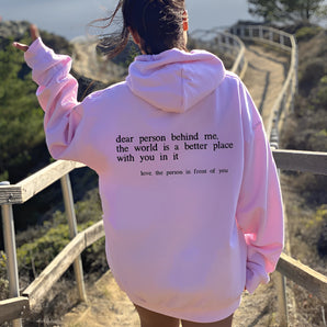Pink tie-dye hoodie with a motivational quote, featuring long sleeves and a relaxed fit, worn by a person enjoying leisure time outdoors in a grassy area.