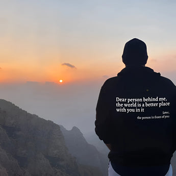 Pink tie-dye hoodie with the words "Self-Love" printed on the front against a backdrop of a serene mountain landscape during sunrise.