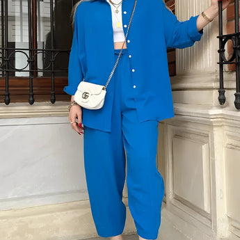Woman wearing a blue high-waist pants, blazer, and crop top set, standing and posing.