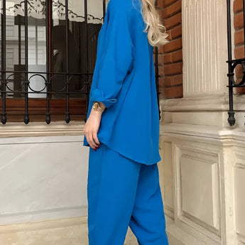 Woman wearing a pink trouser suit with a blazer, high-waist pants, and a crop top.