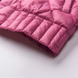 Pink women's lightweight quilted jacket with a diamond pattern, displayed on a couch with decorative pillows in the background.